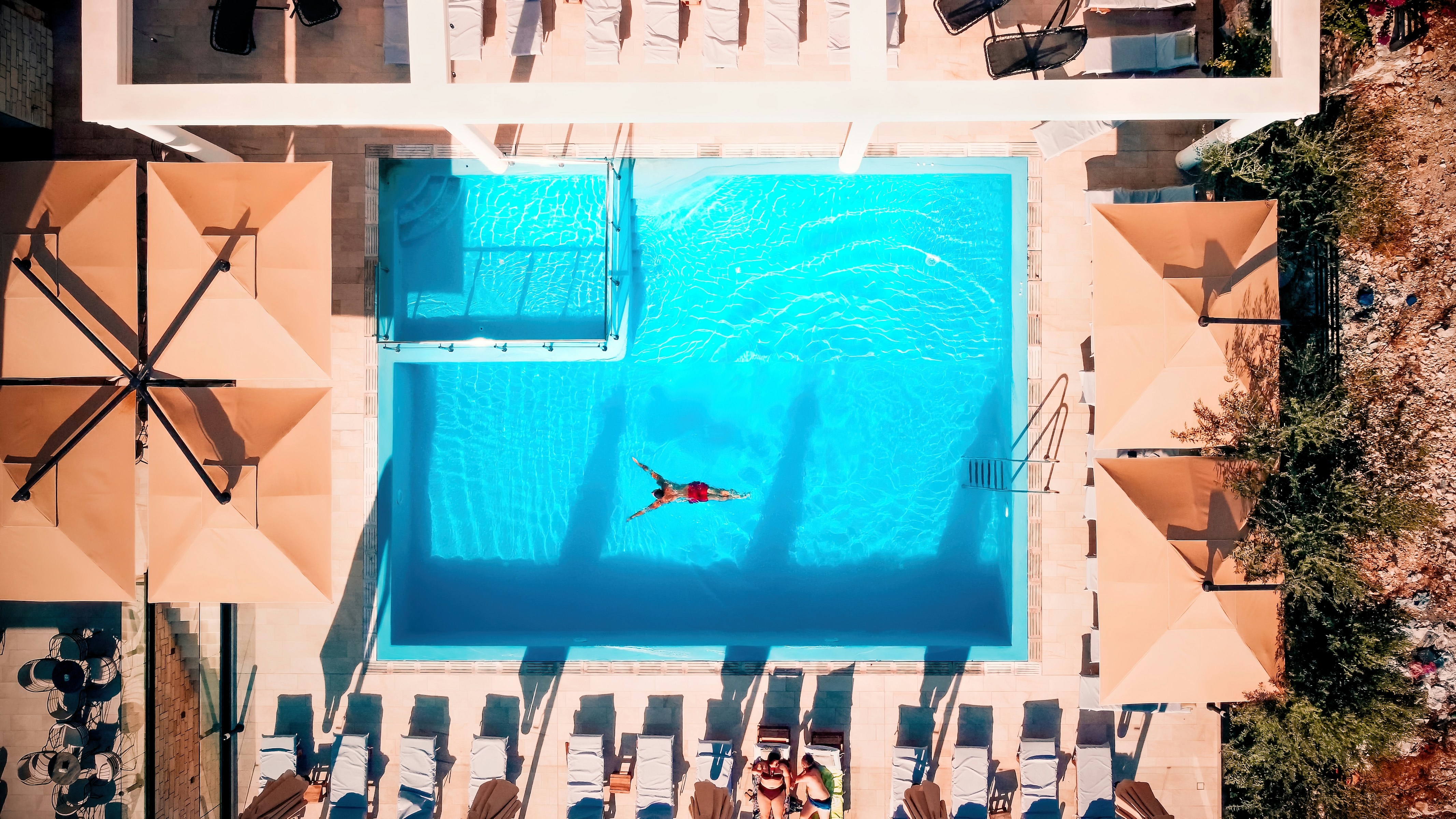 vy ovanifrån på ett hotell med pool och en man som simmar