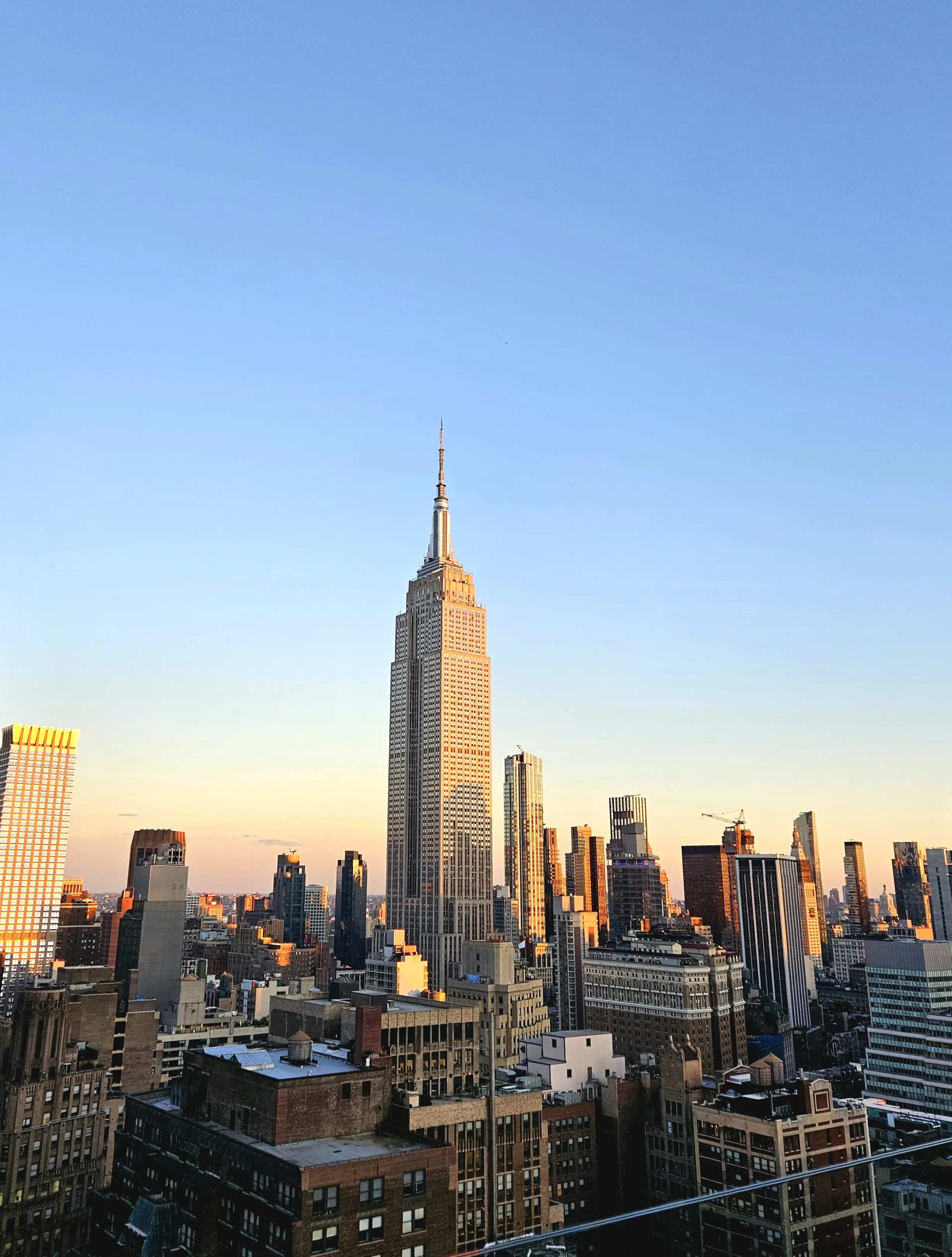 View of New York City focusing on Empire State Building with blue sky in the background