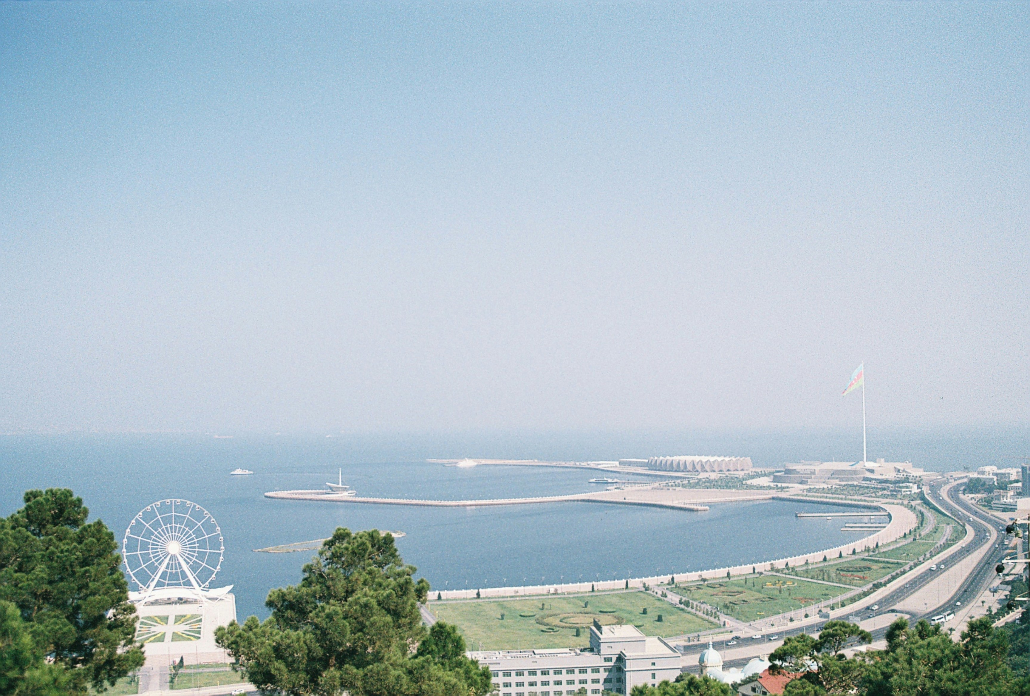 Kusthamn med strand i Baku möter blått hav och dimmig blå himmel i bakgrunden