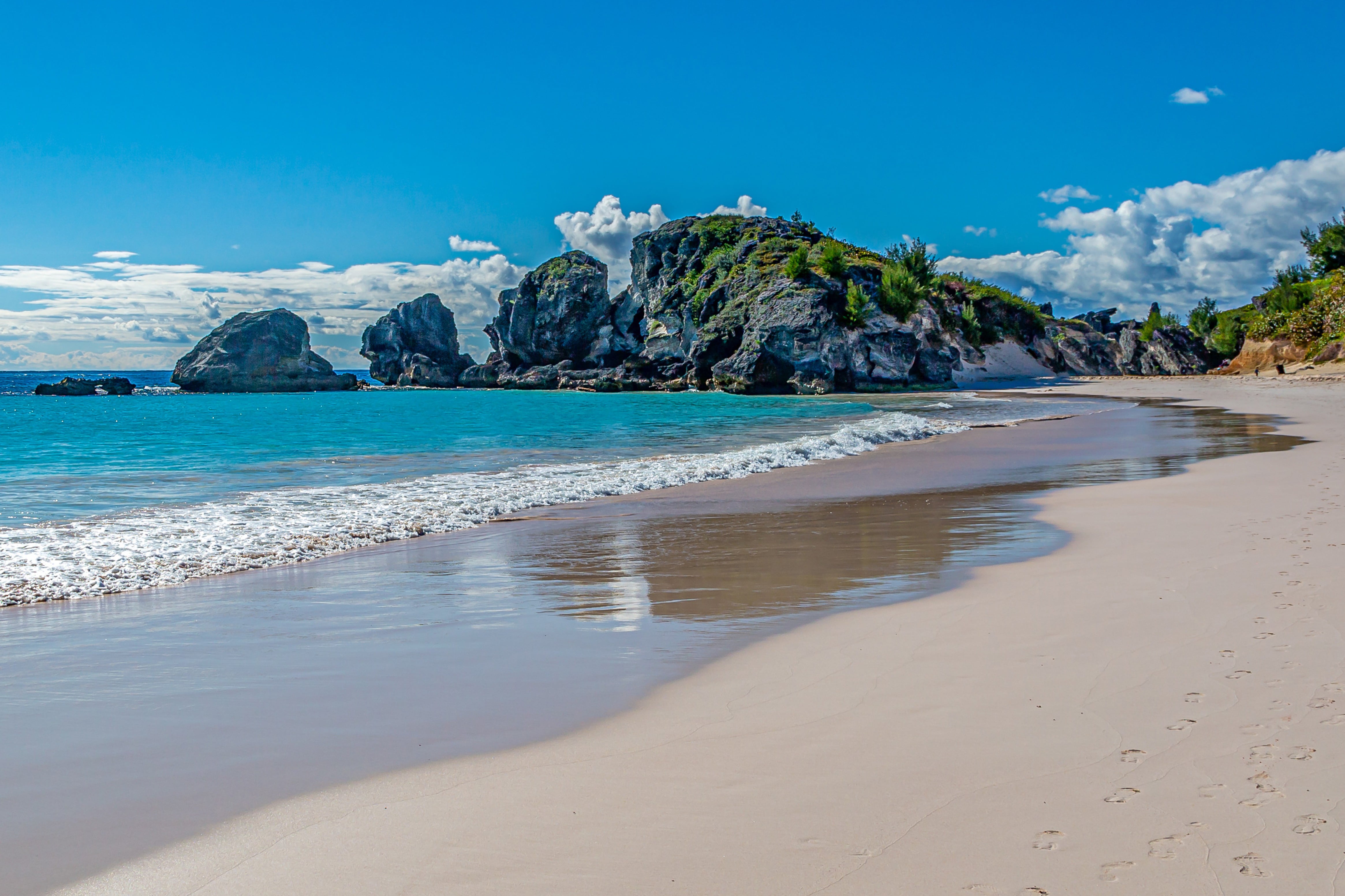 Resa till Bermuda - Vacker stillsam vit strand med turkosblått vatten med klippor och blå himmel i bakgrunden