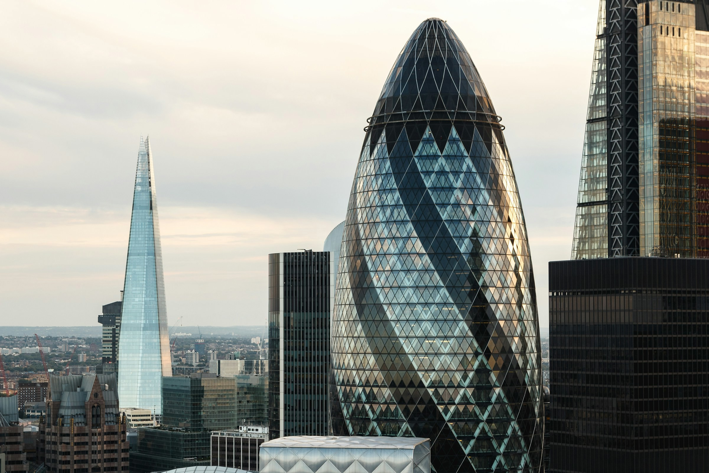 Panoramic views of the London skyline with the iconic skyscraper The Shard and the Gherkin Building in the foreground at dusk.