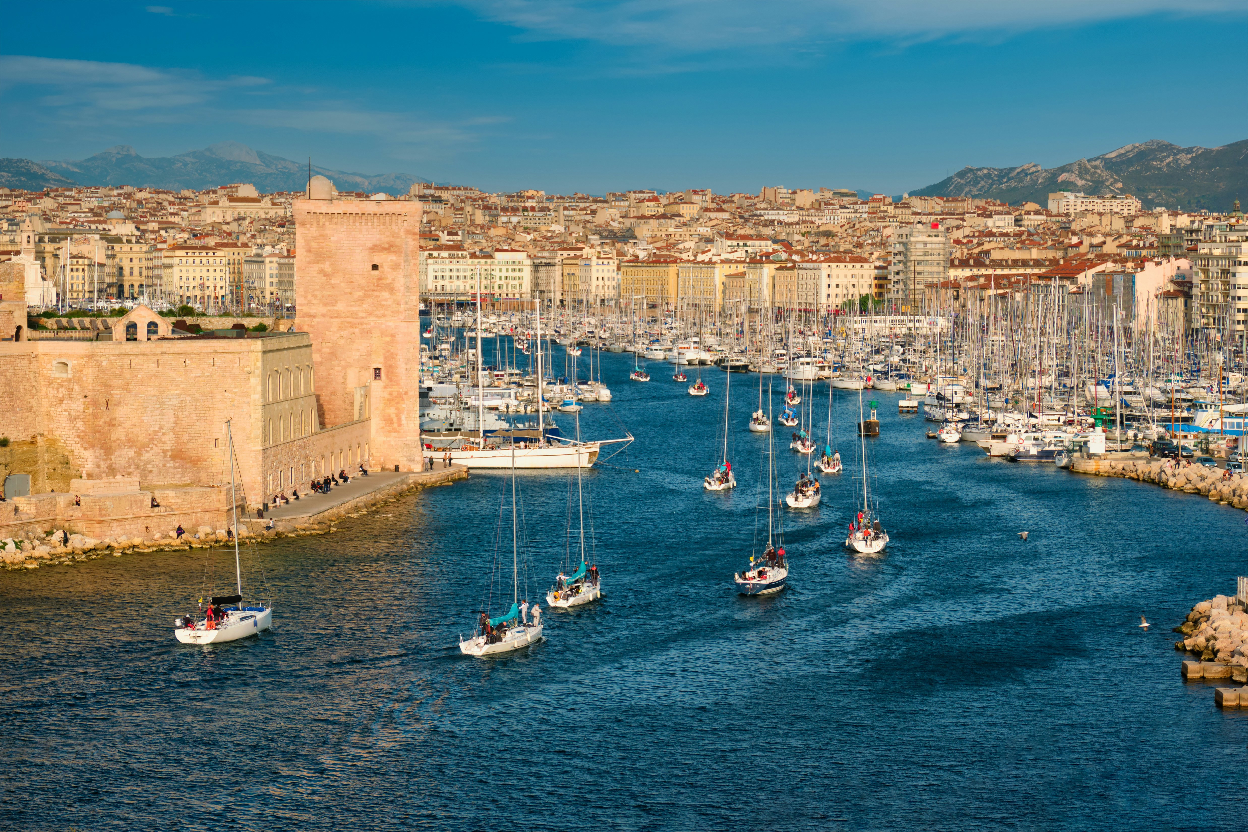 hamn med båtar påväg in med stad i bakgrunden