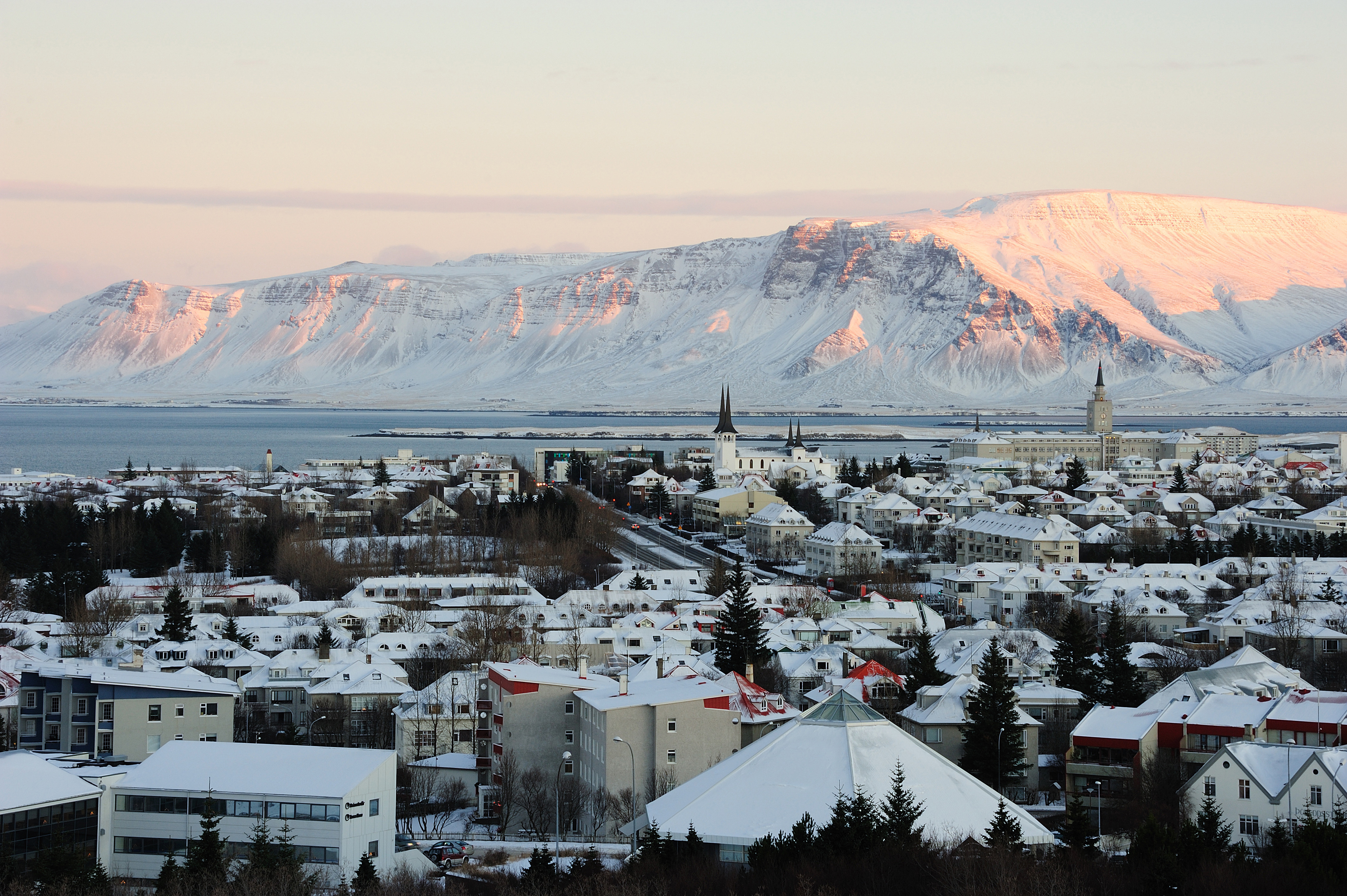 Näkymä Reykjavikin kaupunkiin, jossa vuoret taustalla auringonlaskun aikaan