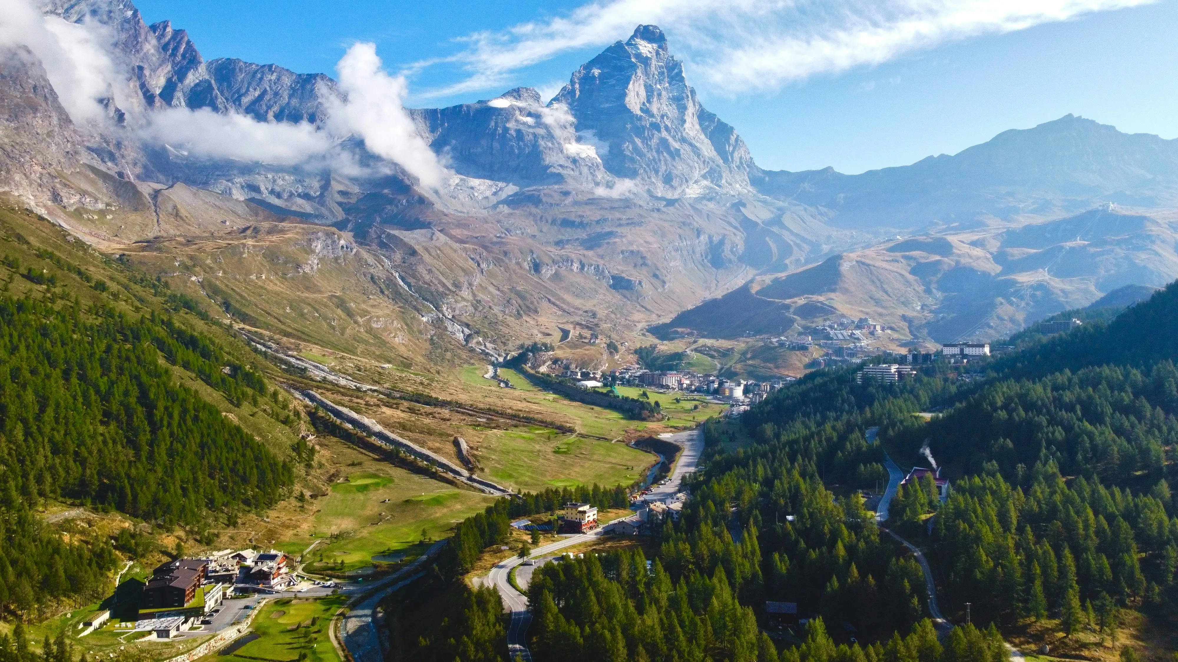 Travel to Cervinia - Mountain scenery with picturesque village and clouds around the mountain peaks under clear skies.