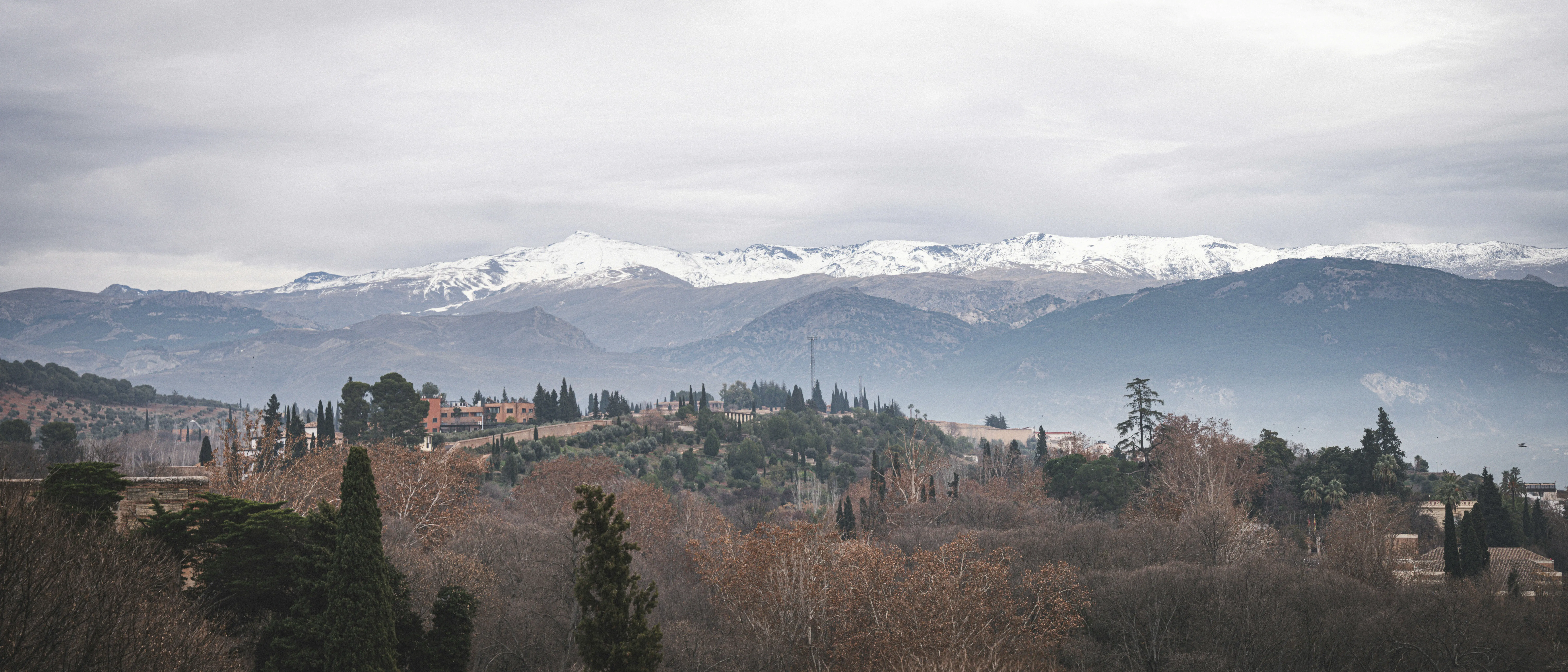 Travel to Sierra Nevada - Panoramic view of mountain range in Spain with snow-capped peaks and cloudy skies