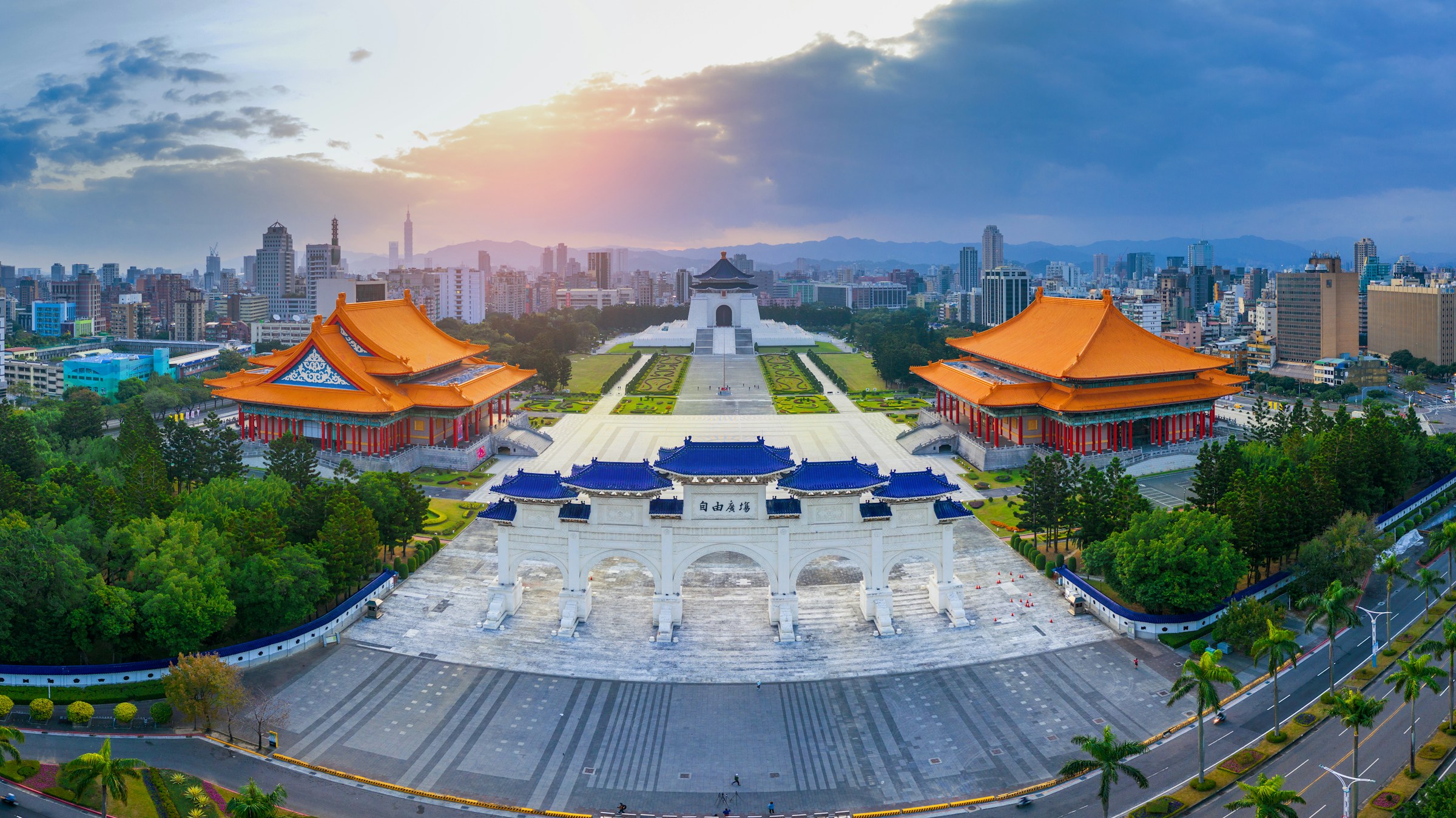 Panorama vy över torg och tempel i Taipei omgivna av grönska och en soluppgång i bakgrunden