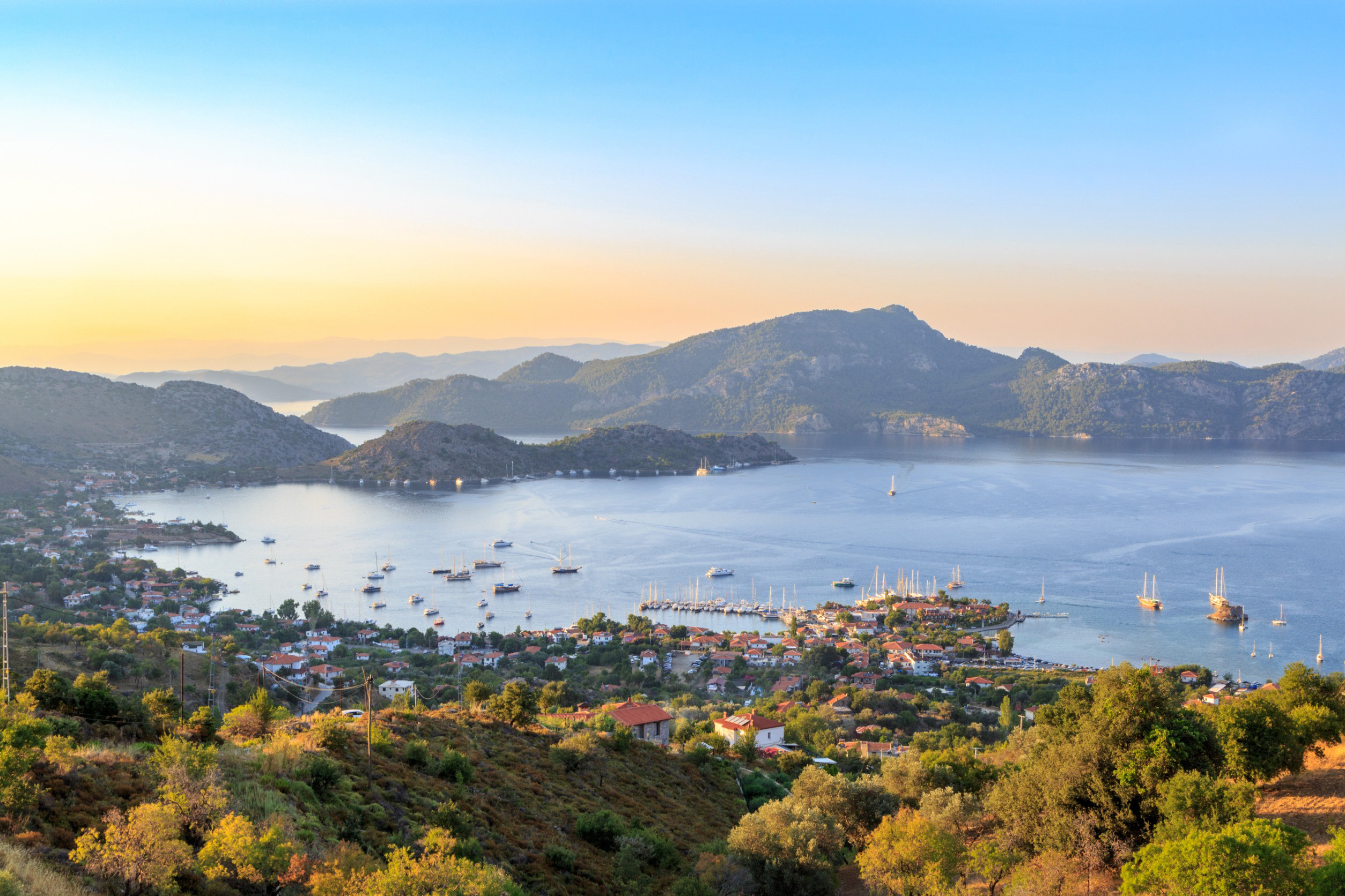 Panoramavy över Marmaris-stad i Turkiet med grönskande träd, byggnader, en stad som möter havet och berg i bakgrunden