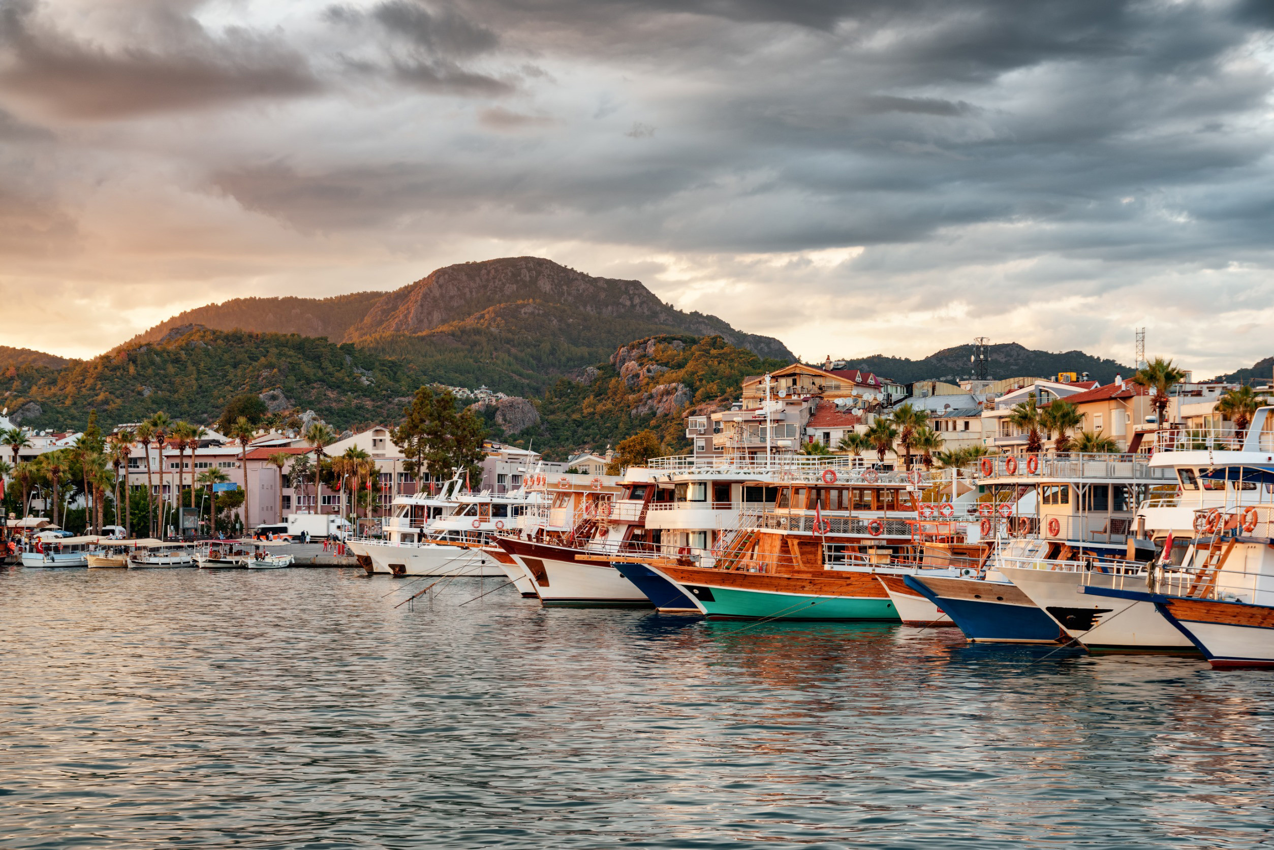 Solnedgång vid en hamn i Marmaris fylld med båtar och vackra berg i bakgrunden