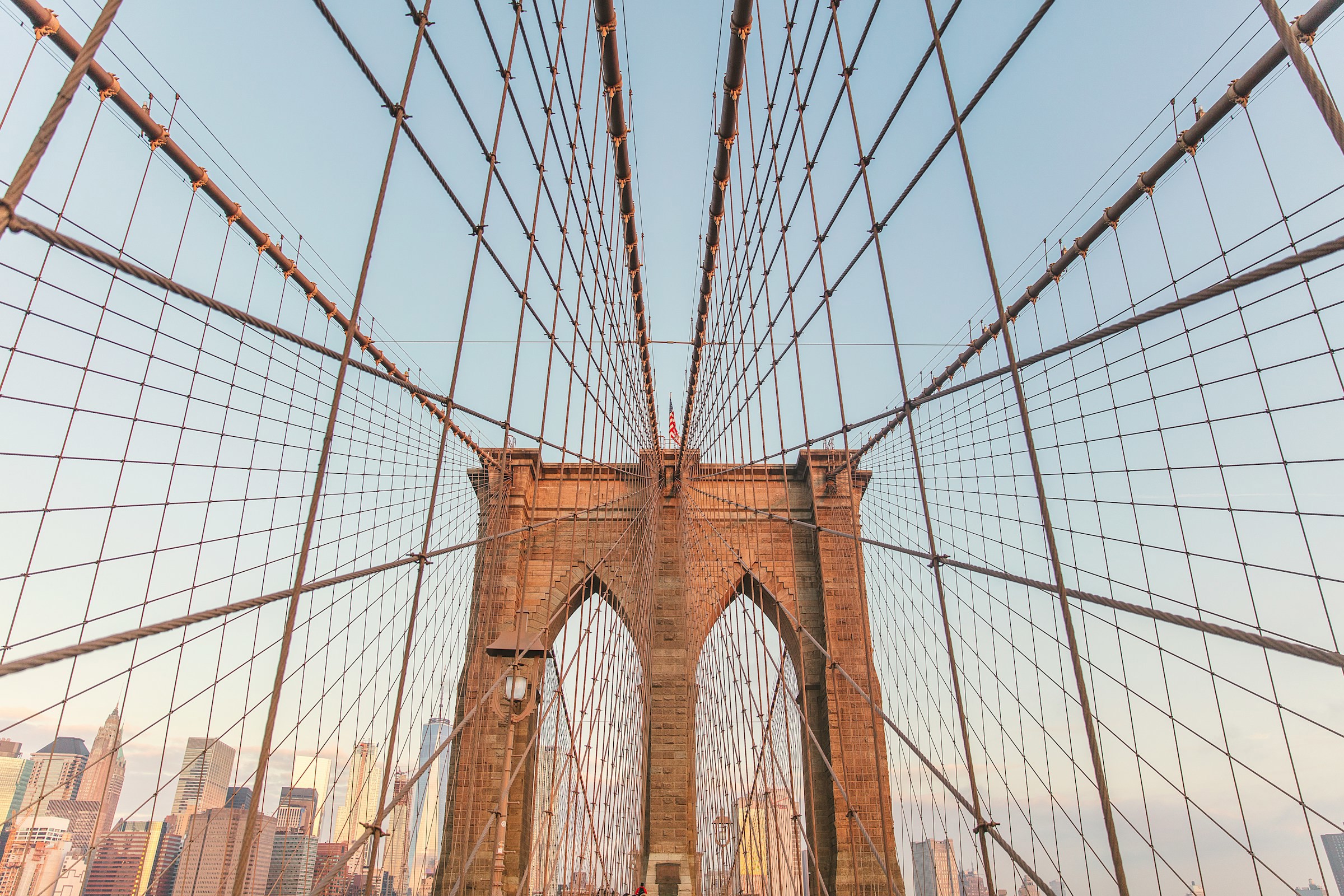 View from below up to the iconic Brooklyn Bridge in New York with Brooklyn in the background