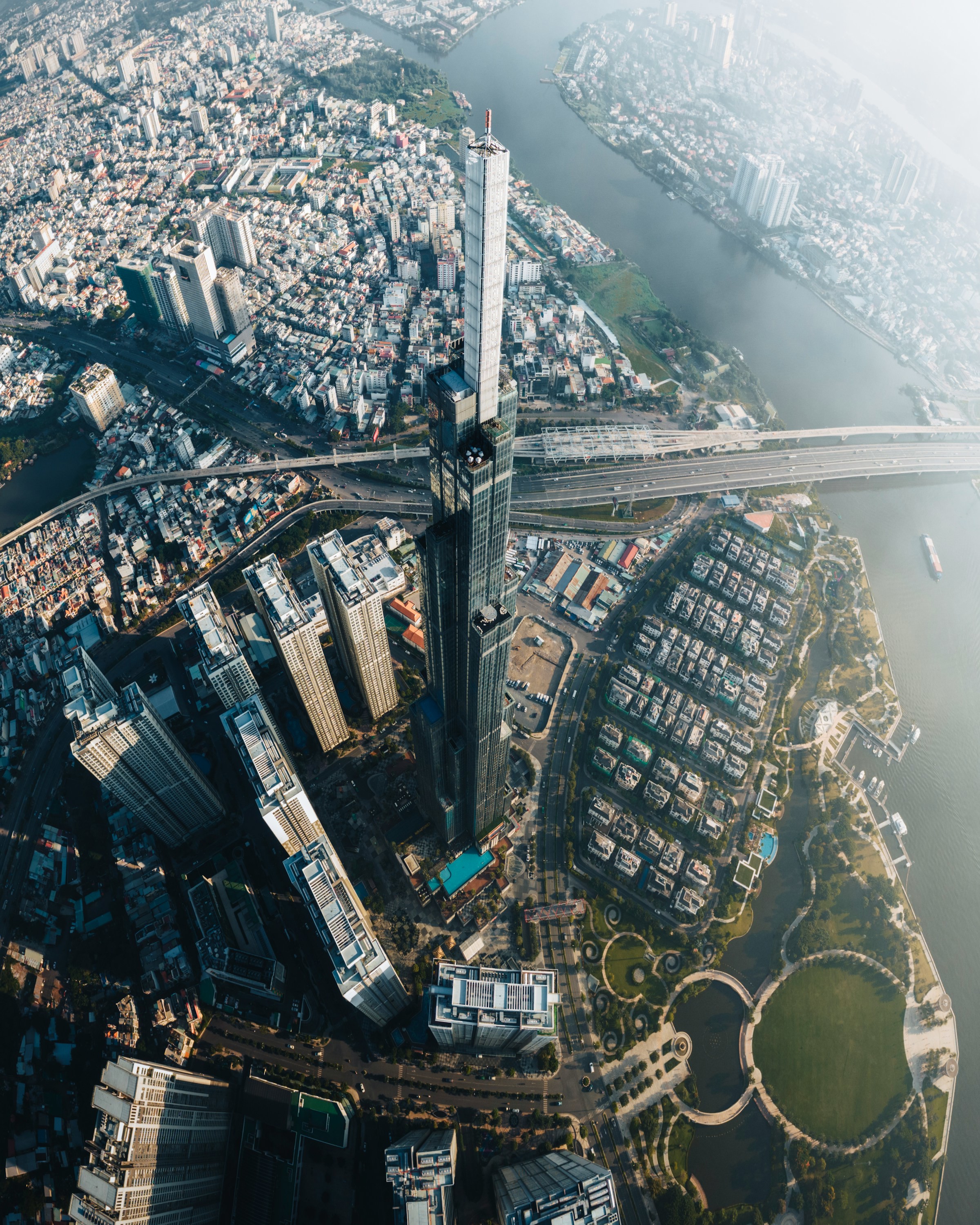 Ilmakuva Ho Chi Minh Citystä veden äärellä korkeilla pilvenpiirtäjillä ja silloilla kaupunkimaisemassa.